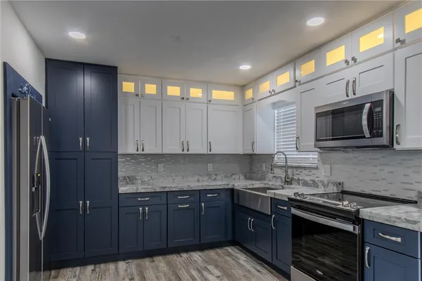 a kitchen with stainless steel appliances granite countertop a stove a sink and a microwave