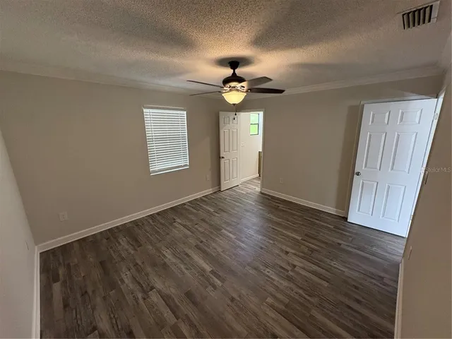 an empty room with wooden floor ceiling fan and window