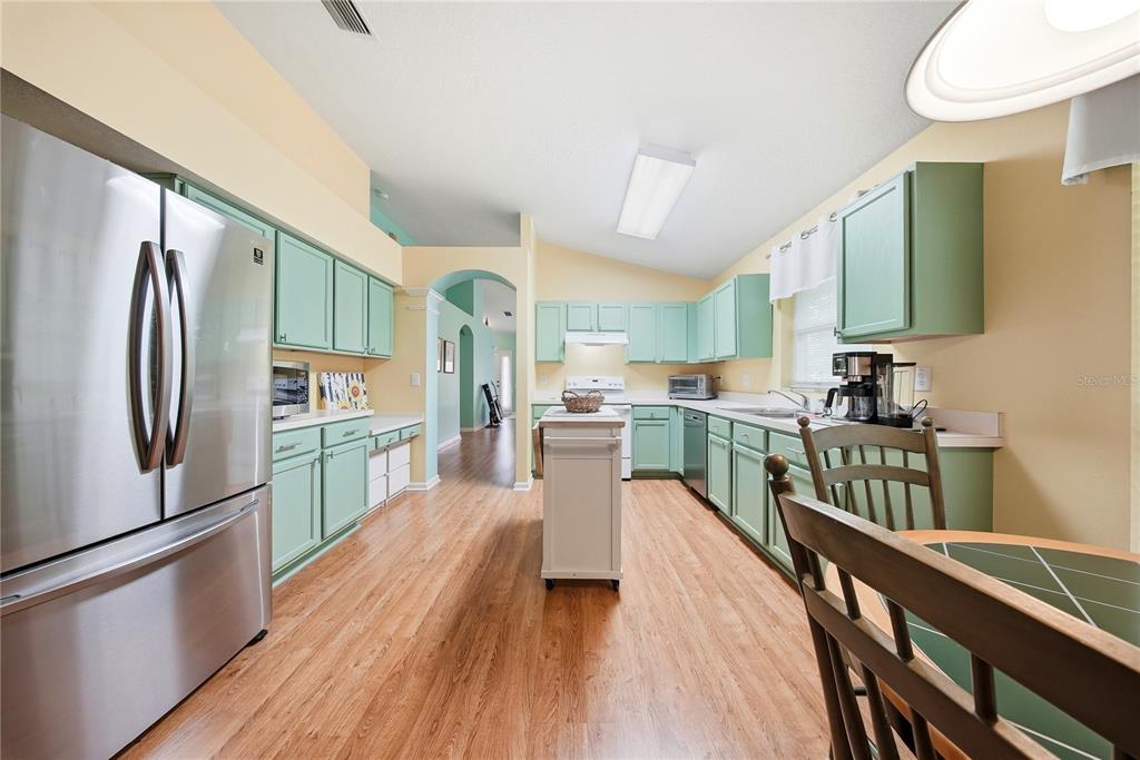 5856 Count Turf Lane Wesley Chapel, FL 33544 - Photo 12 of 57 a kitchen with kitchen island wooden floors stainless steel appliances and sink