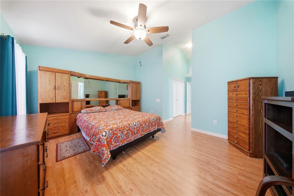 5856 Count Turf Lane Wesley Chapel, FL 33544 - Photo 18 of 57 a bedroom with a bed dresser and a wooden floor