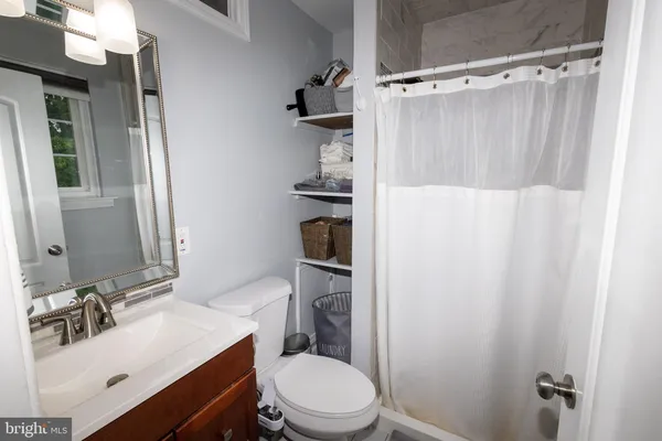 a bathroom with a sink a toilet a mirror and shower