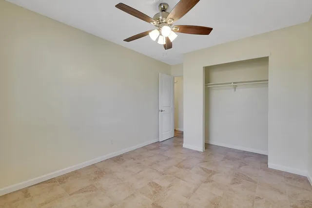 an empty room with closet and a ceiling fan