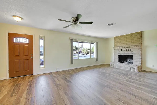 an empty room with windows fireplace and wooden floor