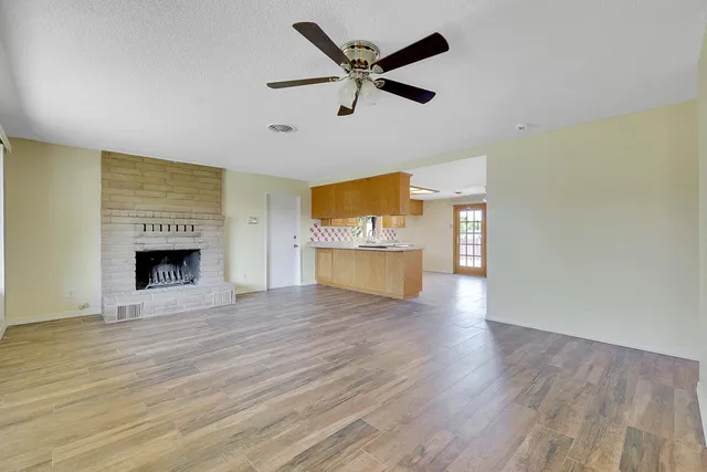 a view of an empty room with a fireplace and wooden floor