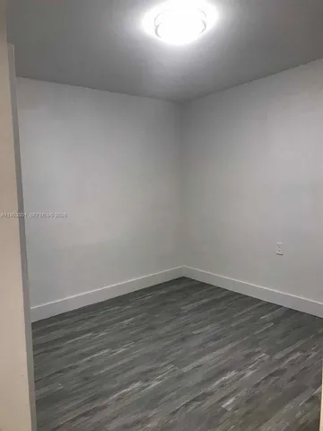 an empty room with wooden floor closet and windows