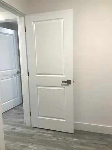 an empty room with wooden floor cabinet and windows