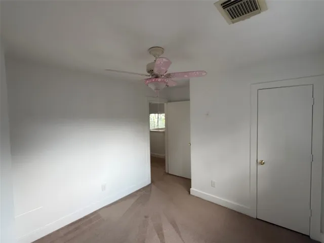 a view of an empty room and chandelier fan