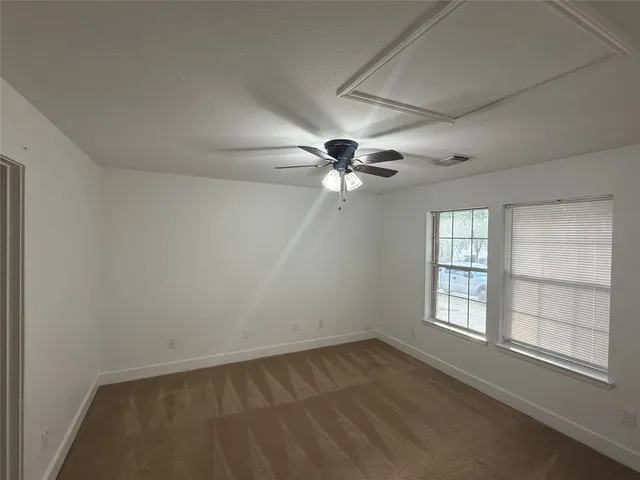 an empty room with a window and a fan