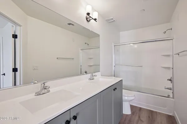 a bathroom with a bathtub shower sink vanity mirror and toilet