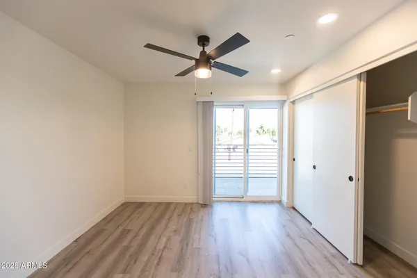 a view of empty room with wooden floor and fan