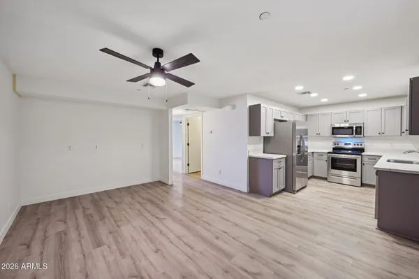 a kitchen with stainless steel appliances a stove top oven a sink dishwasher and a refrigerator with wooden floor