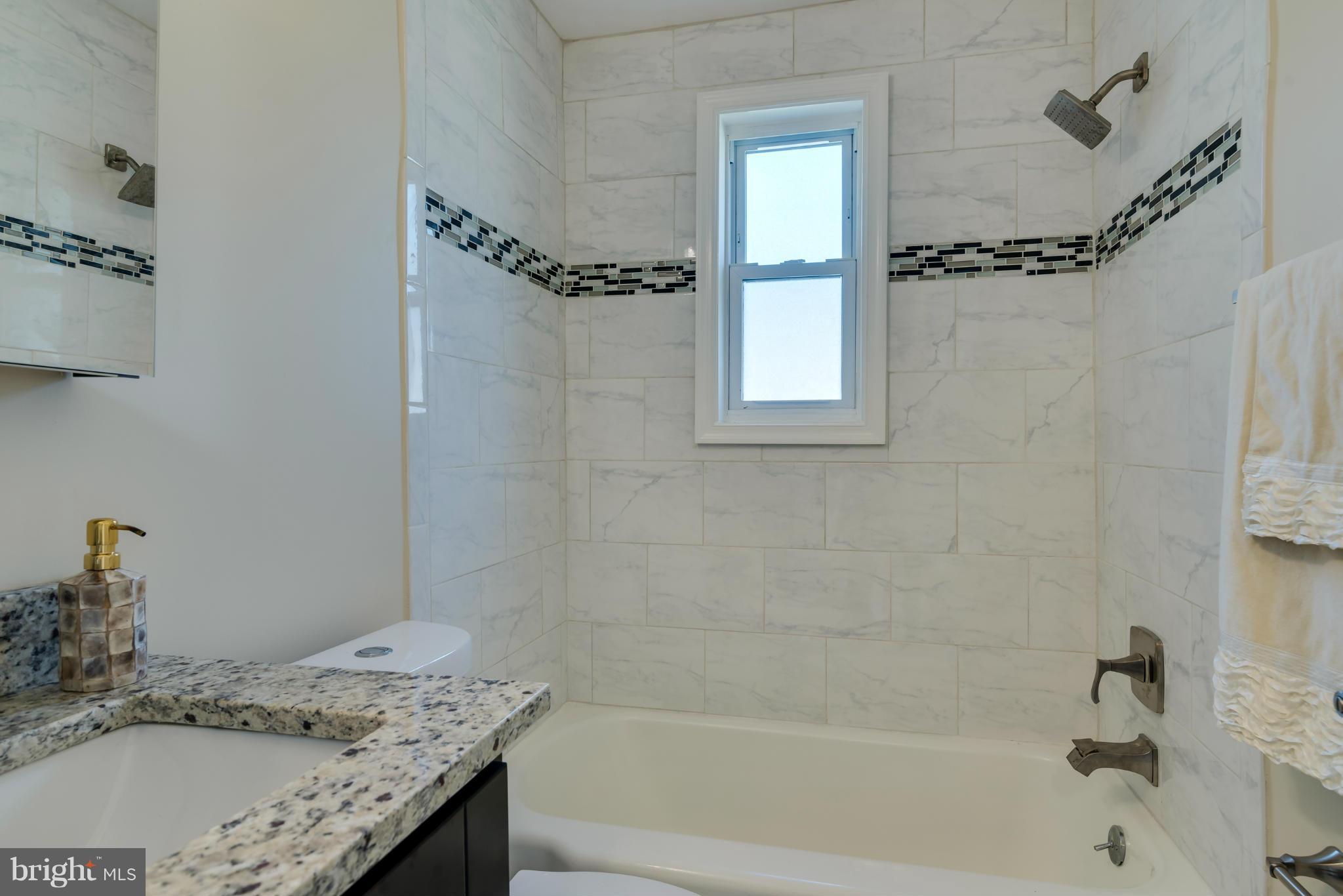 3310 Harrell Street Silver Spring, MD 20906 - Photo 12 of 26 a bathroom with a granite countertop sink a mirror and a bathtub