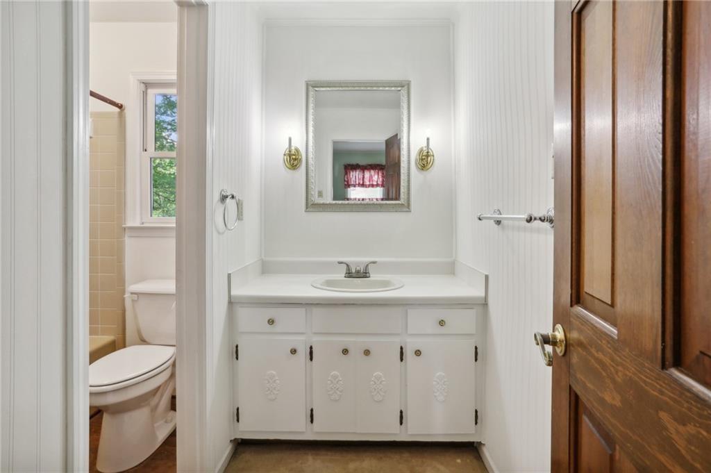 5622 Williamsburg Drive Northwest Norcross, GA 30093 - Photo 26 of 29 a bathroom with a granite countertop toilet a sink and a mirror