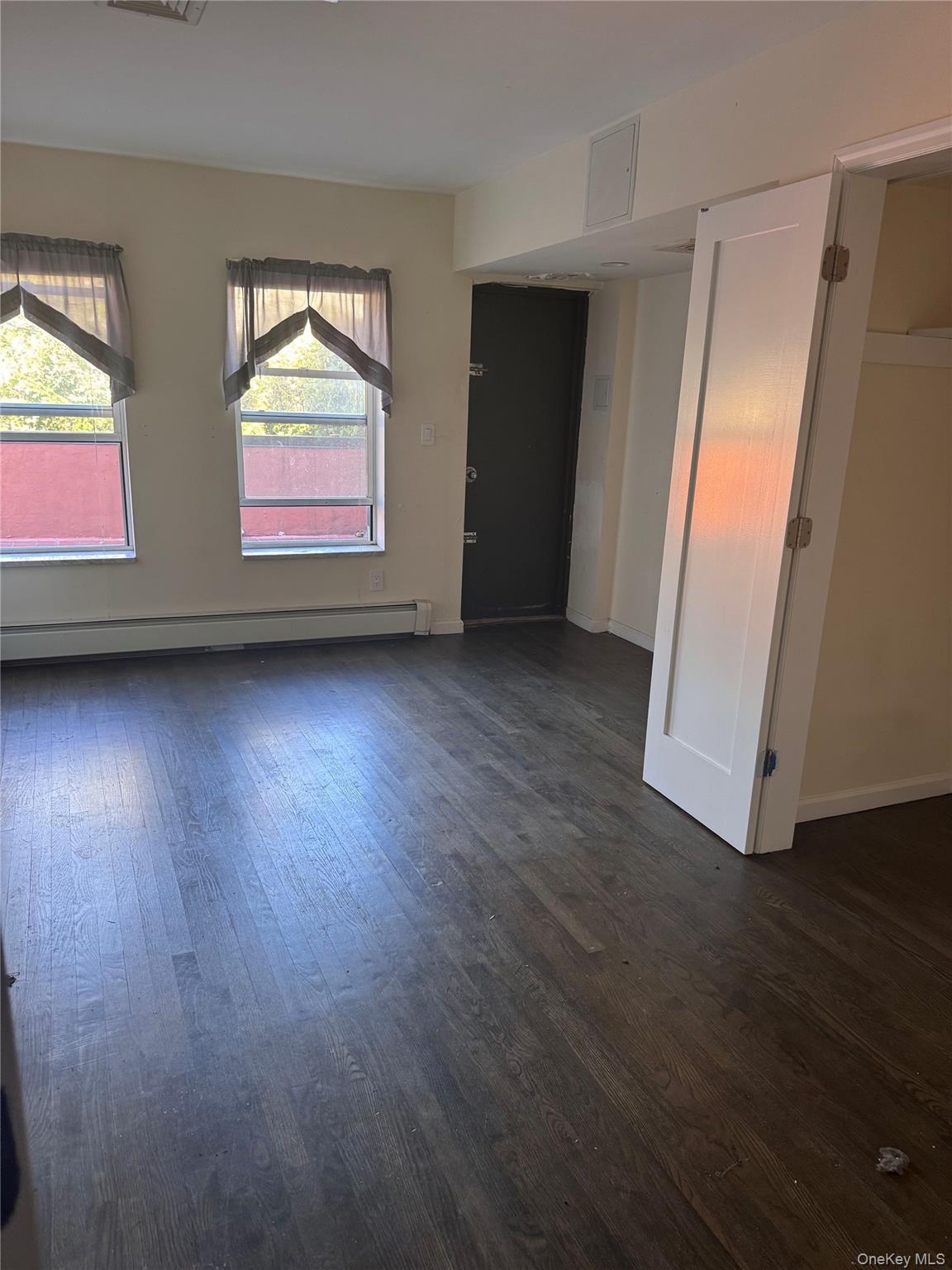 14-27 Astoria Boulevard Queens, NY 11102 - Photo 4 of 11 an empty room with wooden floor and windows