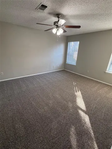 an empty room with windows and chandelier fan