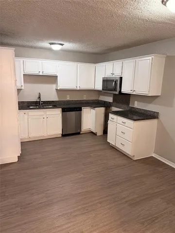a kitchen with granite countertop a stove top oven sink and cabinets