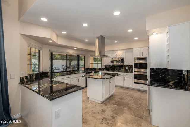 a kitchen with stainless steel appliances kitchen island granite countertop a refrigerator and a stove top oven