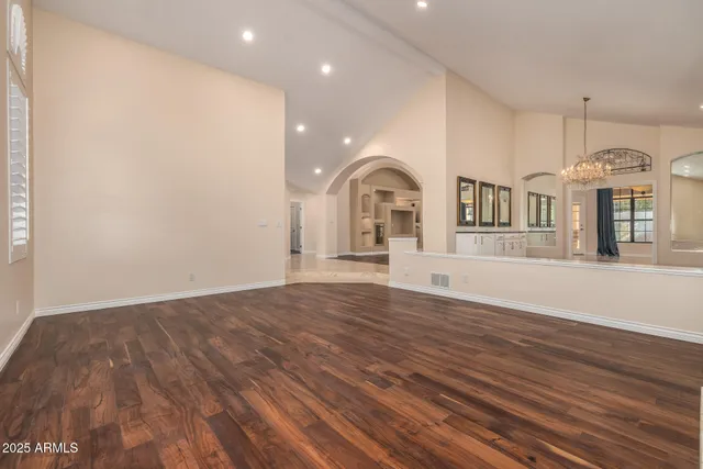 an empty room with wooden floor fireplace and windows