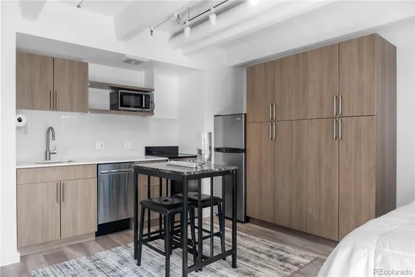 a kitchen with stainless steel appliances a table chairs sink and cabinets