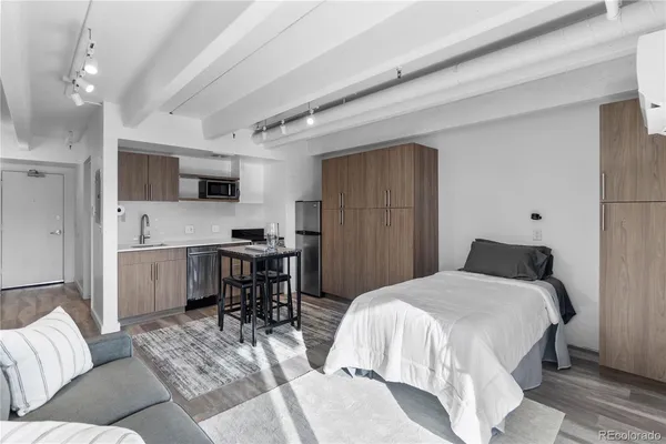 a bedroom with a bed a computer on the desk and a couch