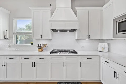 a kitchen with kitchen island granite countertop a sink cabinets a refrigerator and a stove
