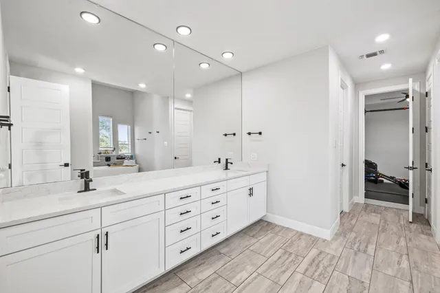 a spacious bedroom with a bed a dresser and a large window