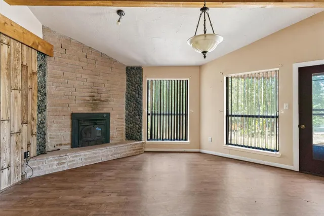 a view of an empty room with a fireplace and a window
