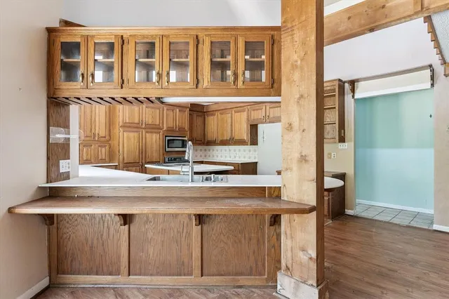 a view of kitchen with stainless steel appliances wooden floor and chair