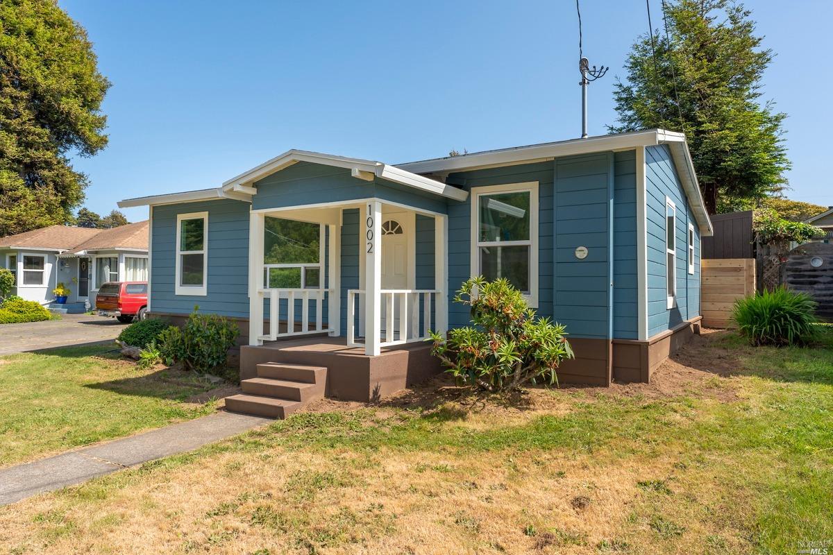 a view of a house with small yard plants and large tree