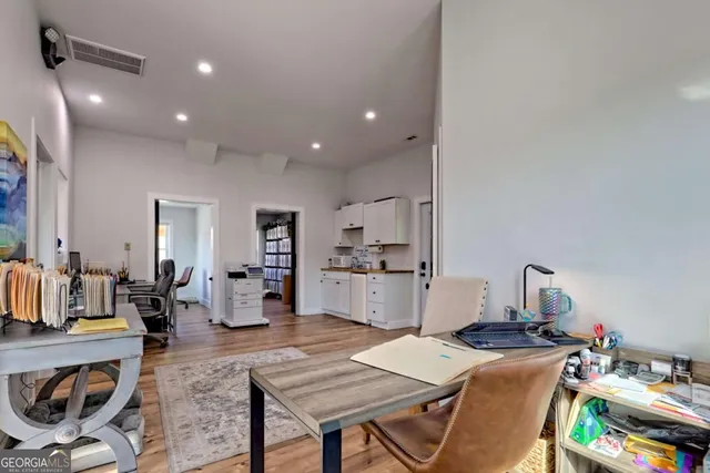 a living room with stainless steel appliances furniture a rug and a kitchen view