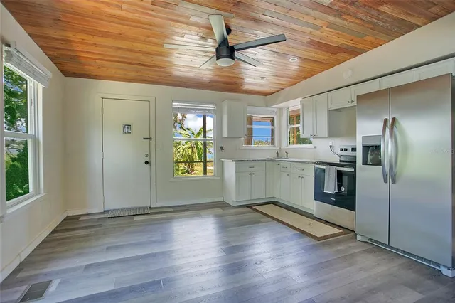 a kitchen with stainless steel appliances granite countertop a refrigerator a sink dishwasher a stove and white countertops with wooden floor