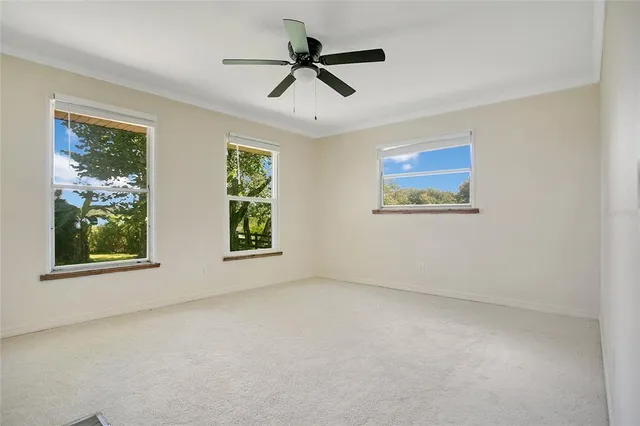 an empty room with windows and ceiling fan