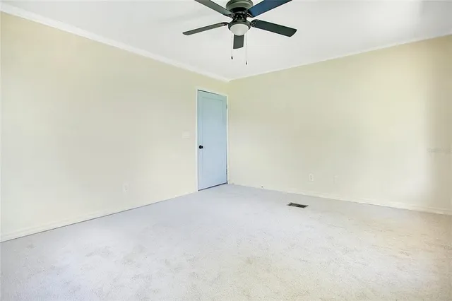 an empty room with a ceiling fan and carpet