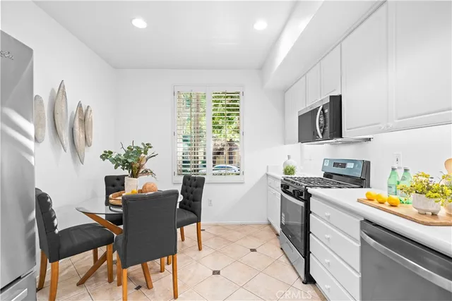 a kitchen with stainless steel appliances a stove a sink a microwave a dining table and chairs