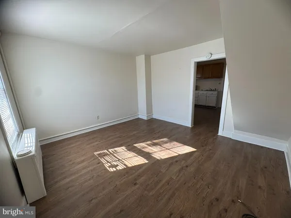 an empty room with wooden floor and natural light
