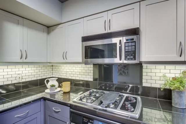 a kitchen with granite countertop stainless steel appliances a stove sink and cabinets