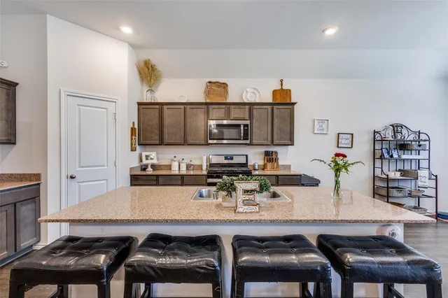 a kitchen with stainless steel appliances a table and chairs in it