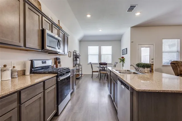 a kitchen with stainless steel appliances granite countertop sink stove top oven and cabinets
