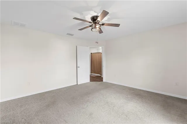 an empty room with window and ceiling fan