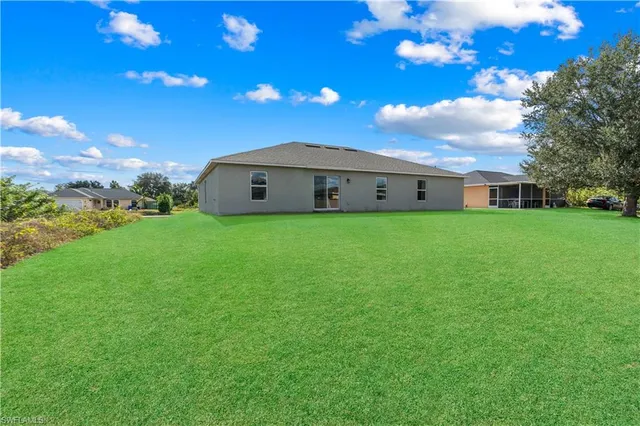 a backyard of a house with plants and large tree