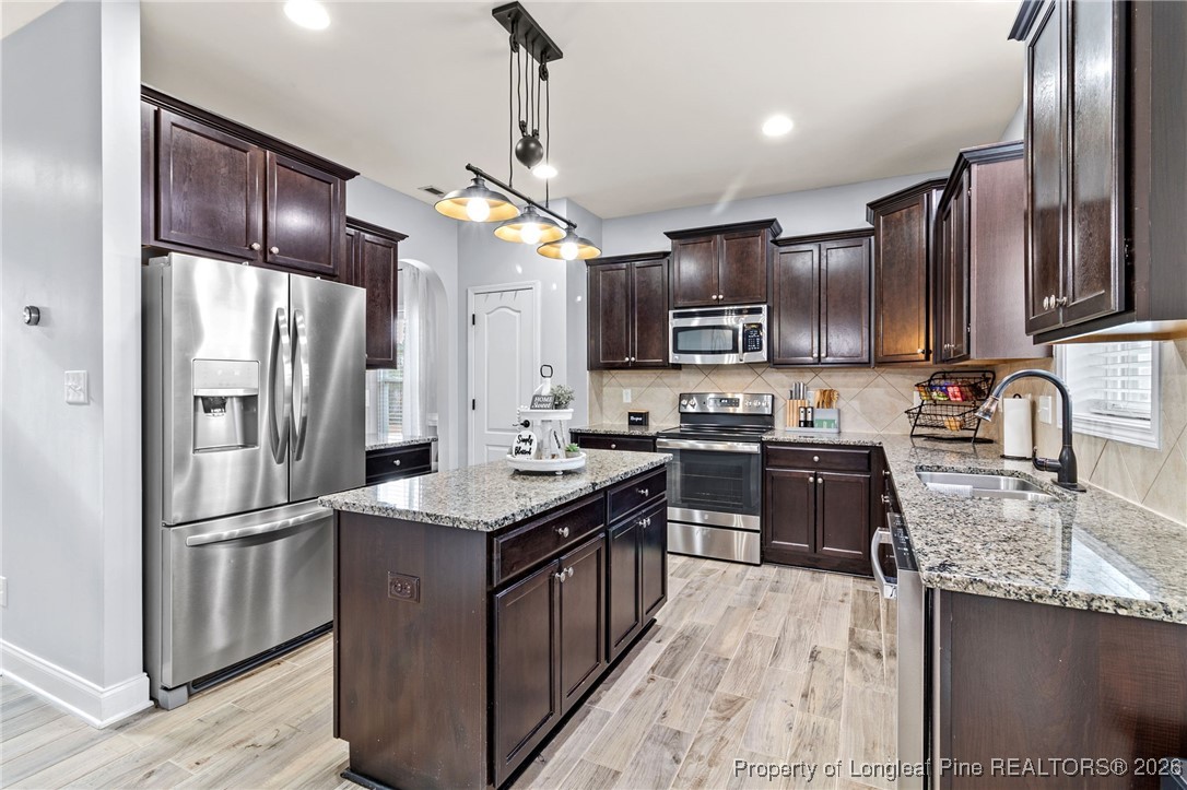 121 Colonist Place Cameron, NC 28326 - Photo 16 of 46 a kitchen with kitchen island granite countertop stainless steel appliances and wooden cabinets
