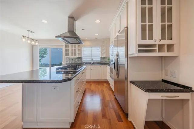 a kitchen with kitchen island granite countertop a stove and a wooden floors