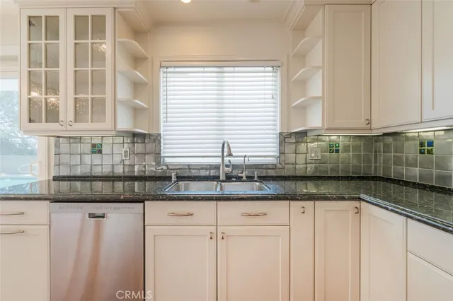a kitchen with granite countertop white cabinets and a window