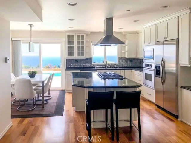 a kitchen with stainless steel appliances a dining table chairs stove and refrigerator