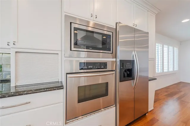 a kitchen with granite countertop white cabinets and stainless steel appliances