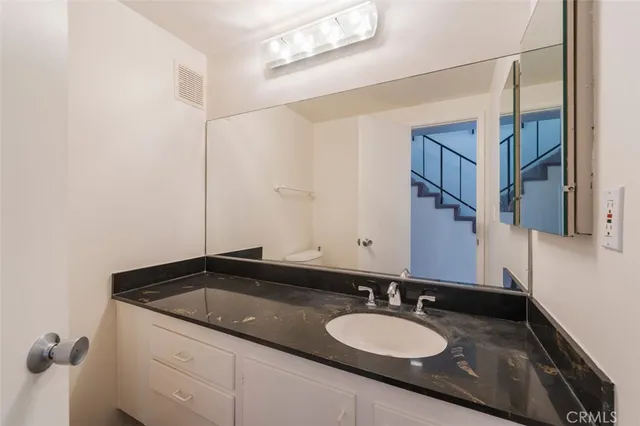a bathroom with a granite countertop sink a mirror and shower