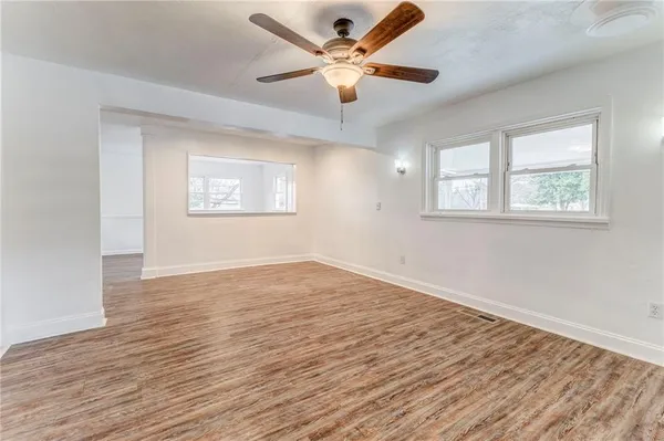 an empty room with chandelier fan and windows