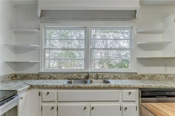 a kitchen with granite countertop a refrigerator a sink dishwasher and white cabinets with wooden floor