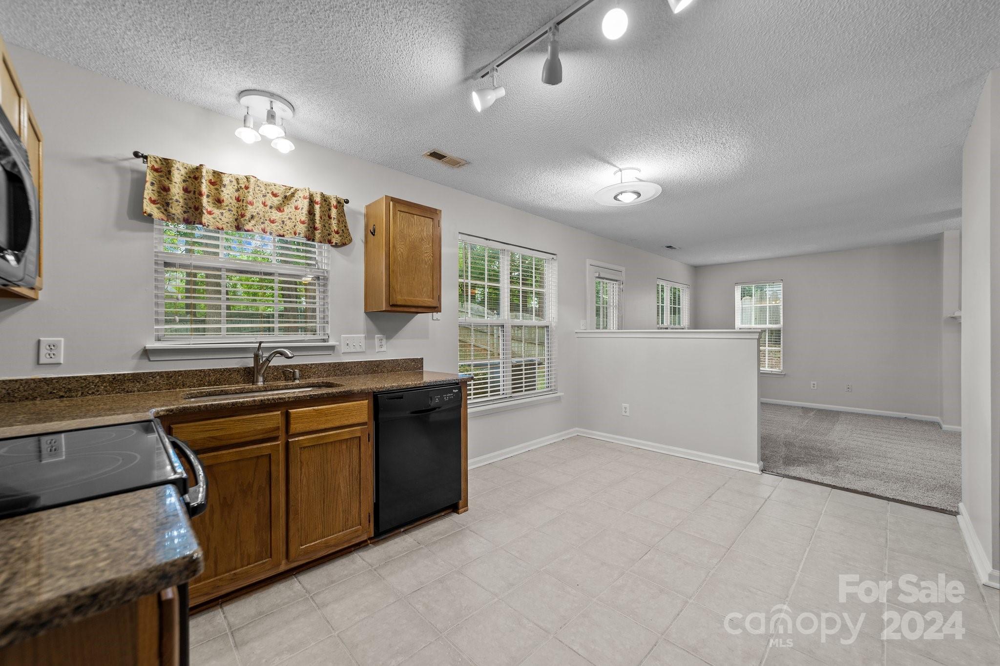 8424 Conner Ridge Lane Charlotte, NC 28269 - Photo 17 of 48 a open kitchen with granite countertop a sink dishwasher stove and cabinets