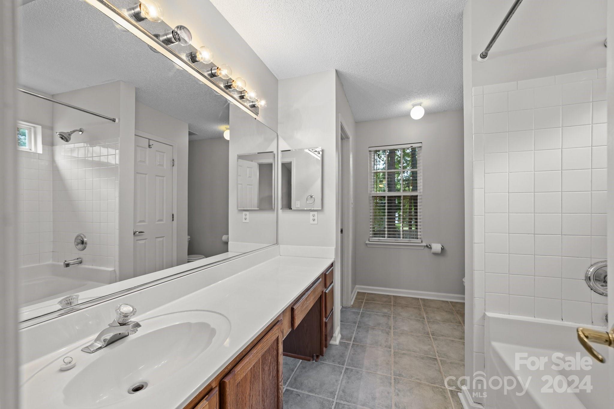 8424 Conner Ridge Lane Charlotte, NC 28269 - Photo 26 of 48 a spacious bathroom with a granite countertop sink a toilet a mirror and shower